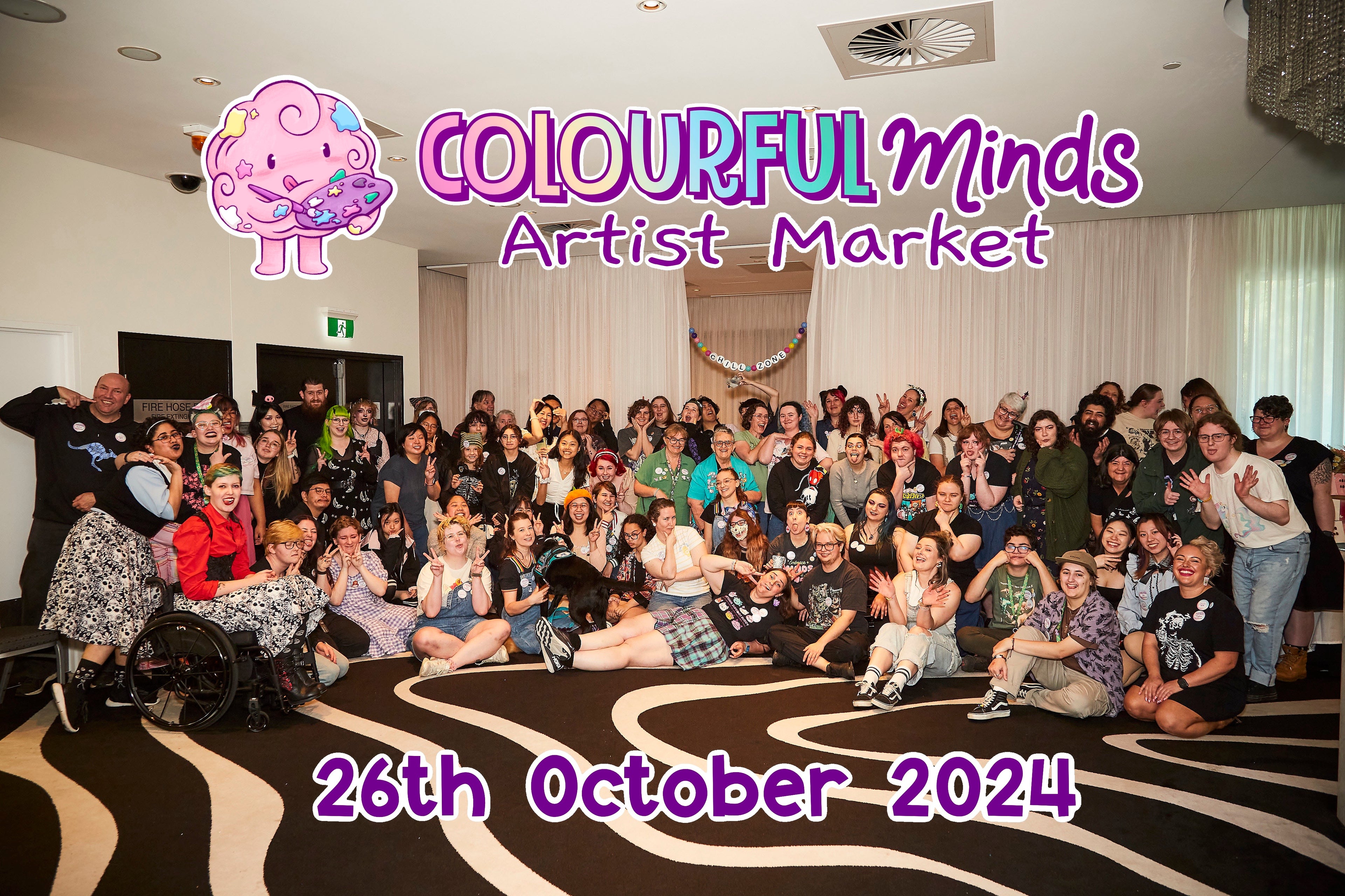Group photo of people at an event with 'Colourful Minds Artist Market' branding.