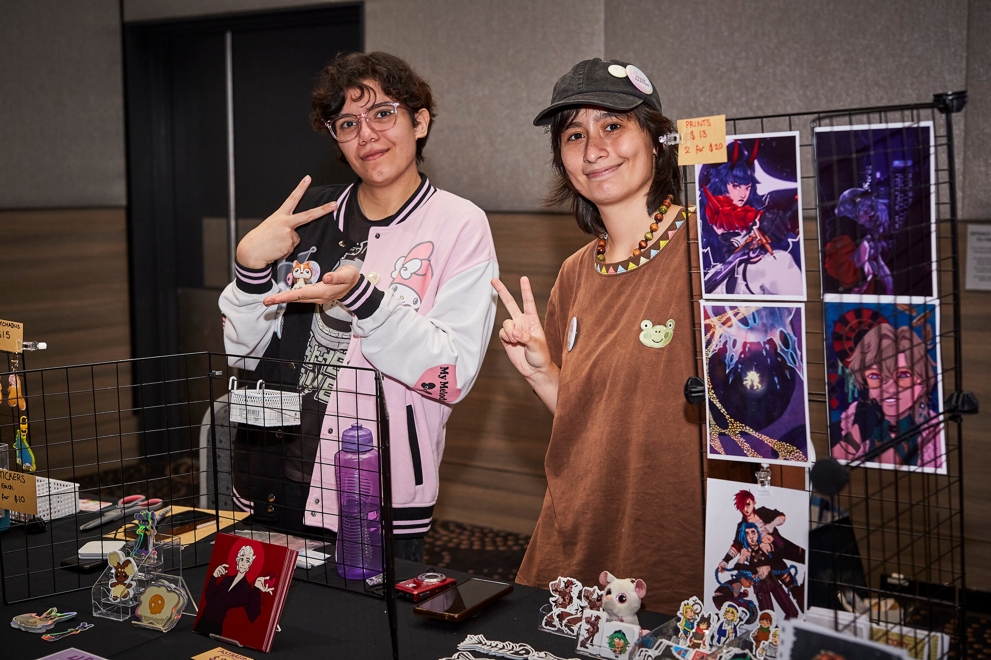 Two people standing behind a display of artwork and merchandise.