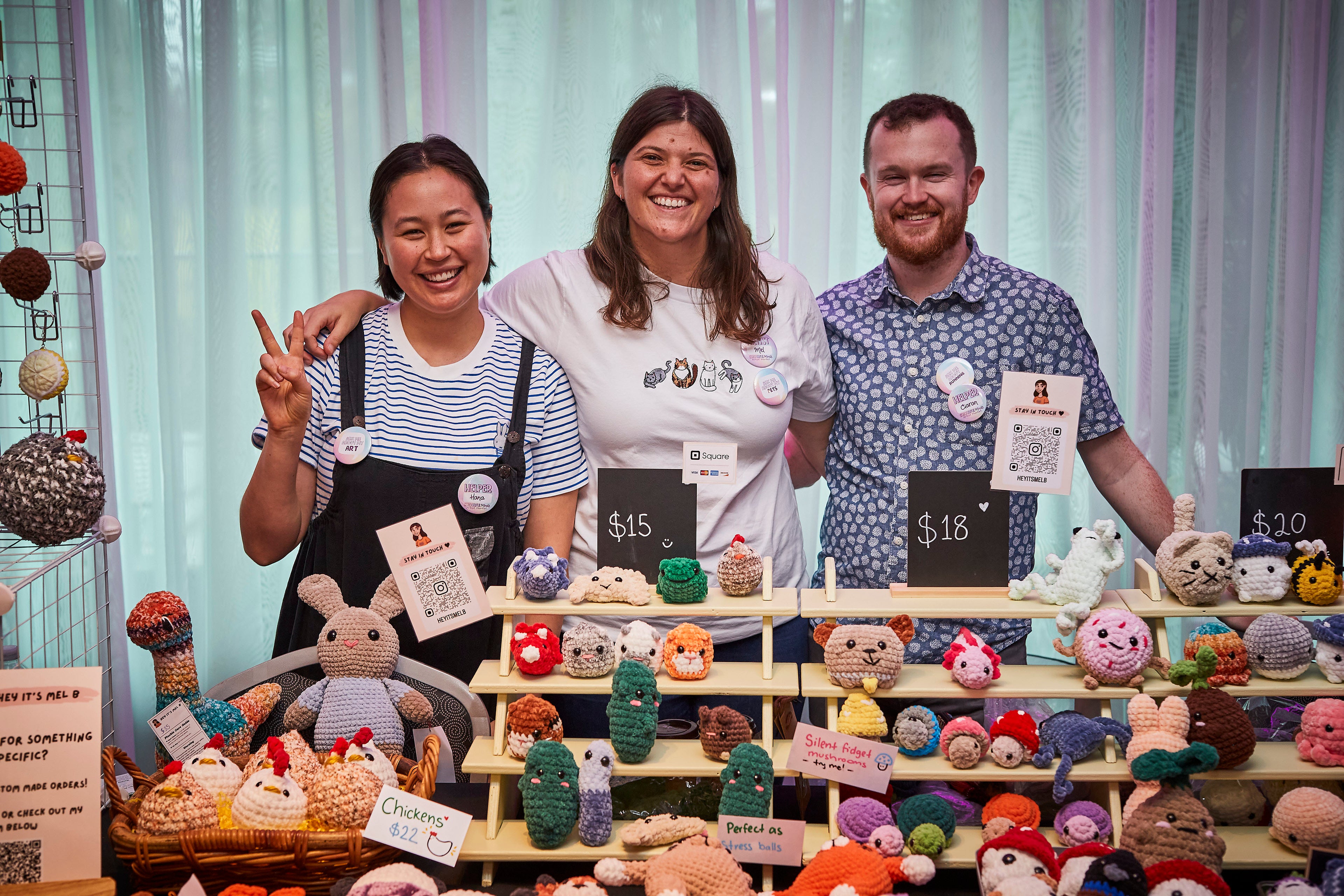 Three people standing behind a table displaying various crocheted items.