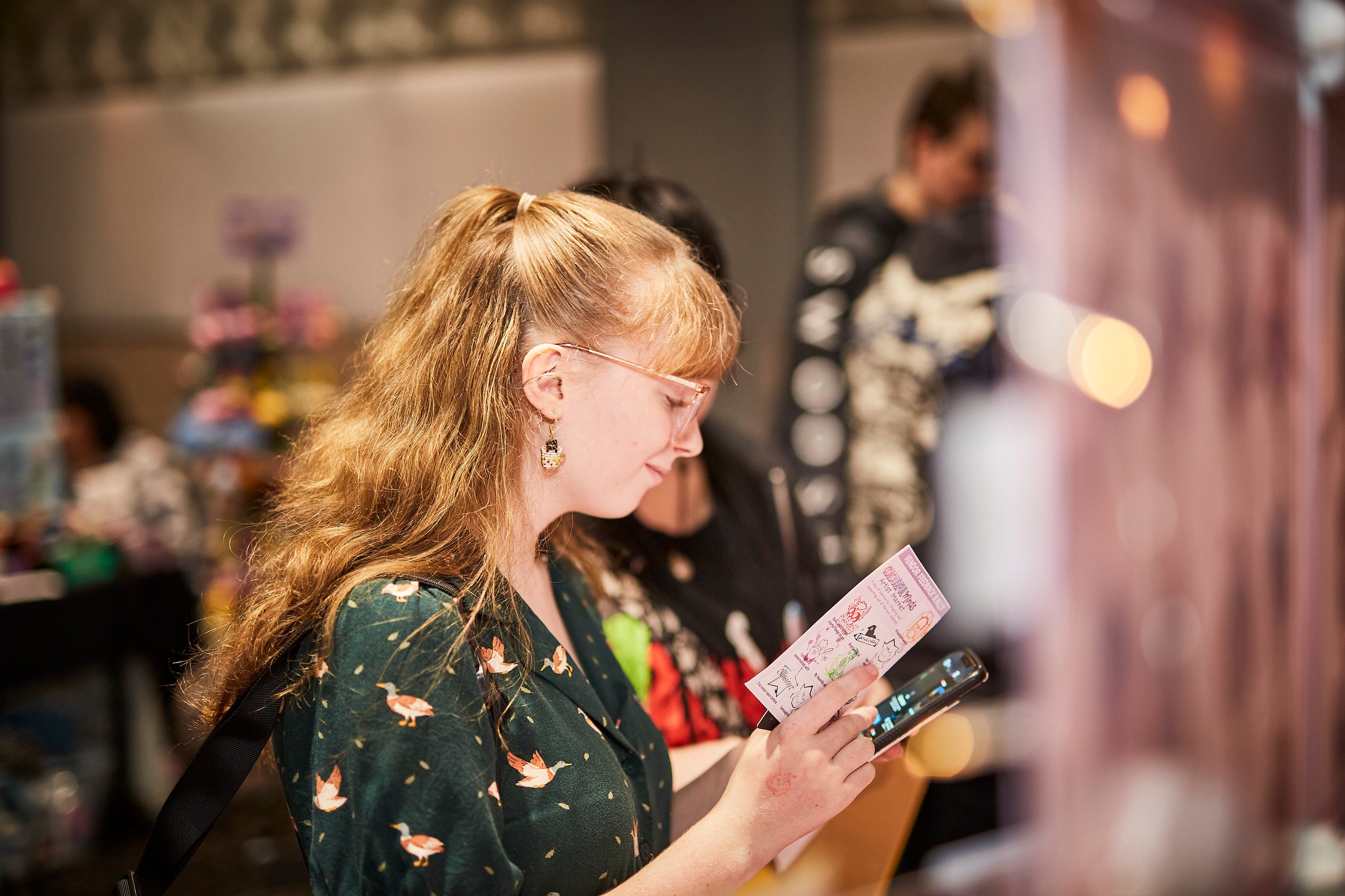 Woman with glasses looking at a phone in a store setting